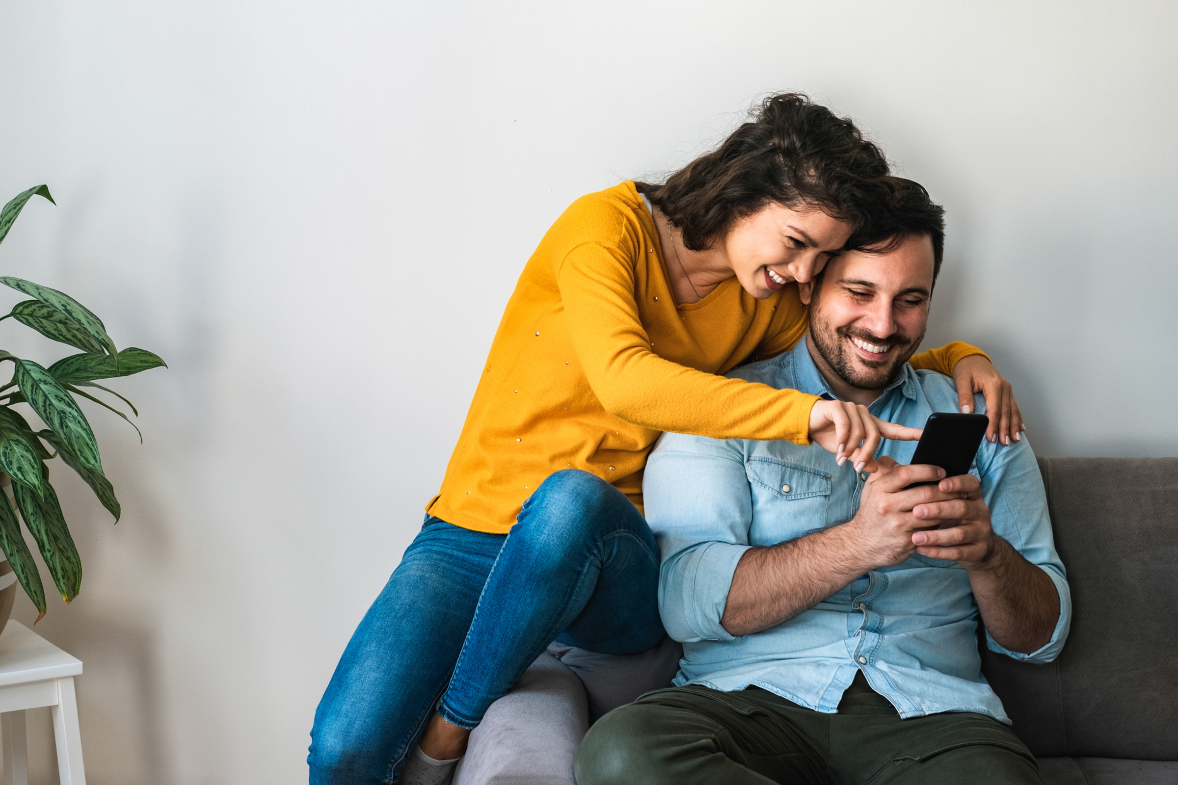 Young couple looking at smartphone together while on couch