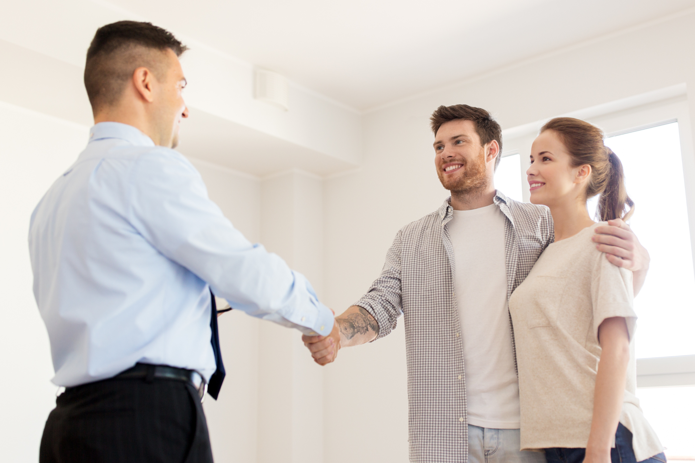 Young couple shaking hands with realtor or sales professional