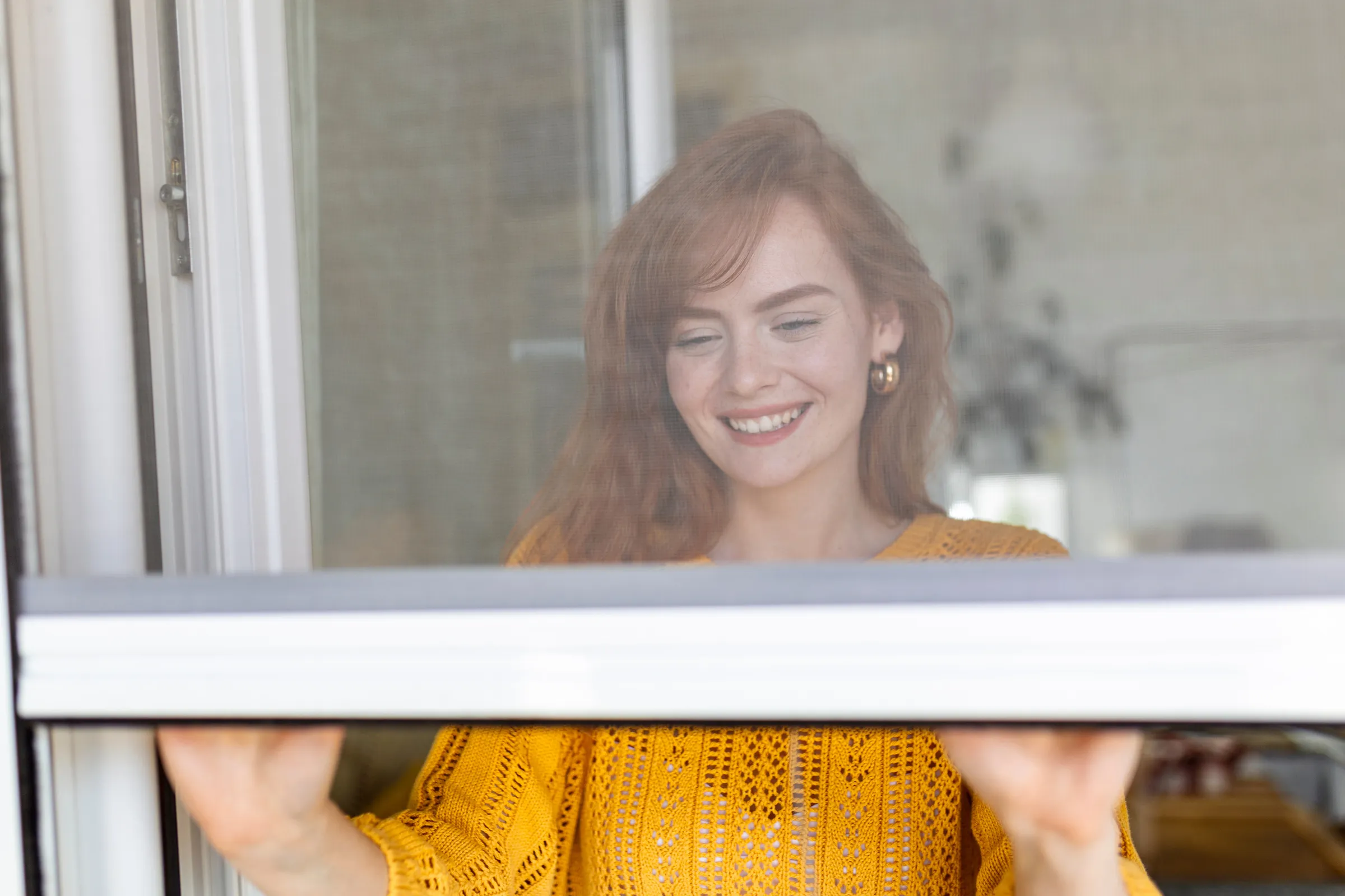 Woman with red hair and yellow sweater shutting window