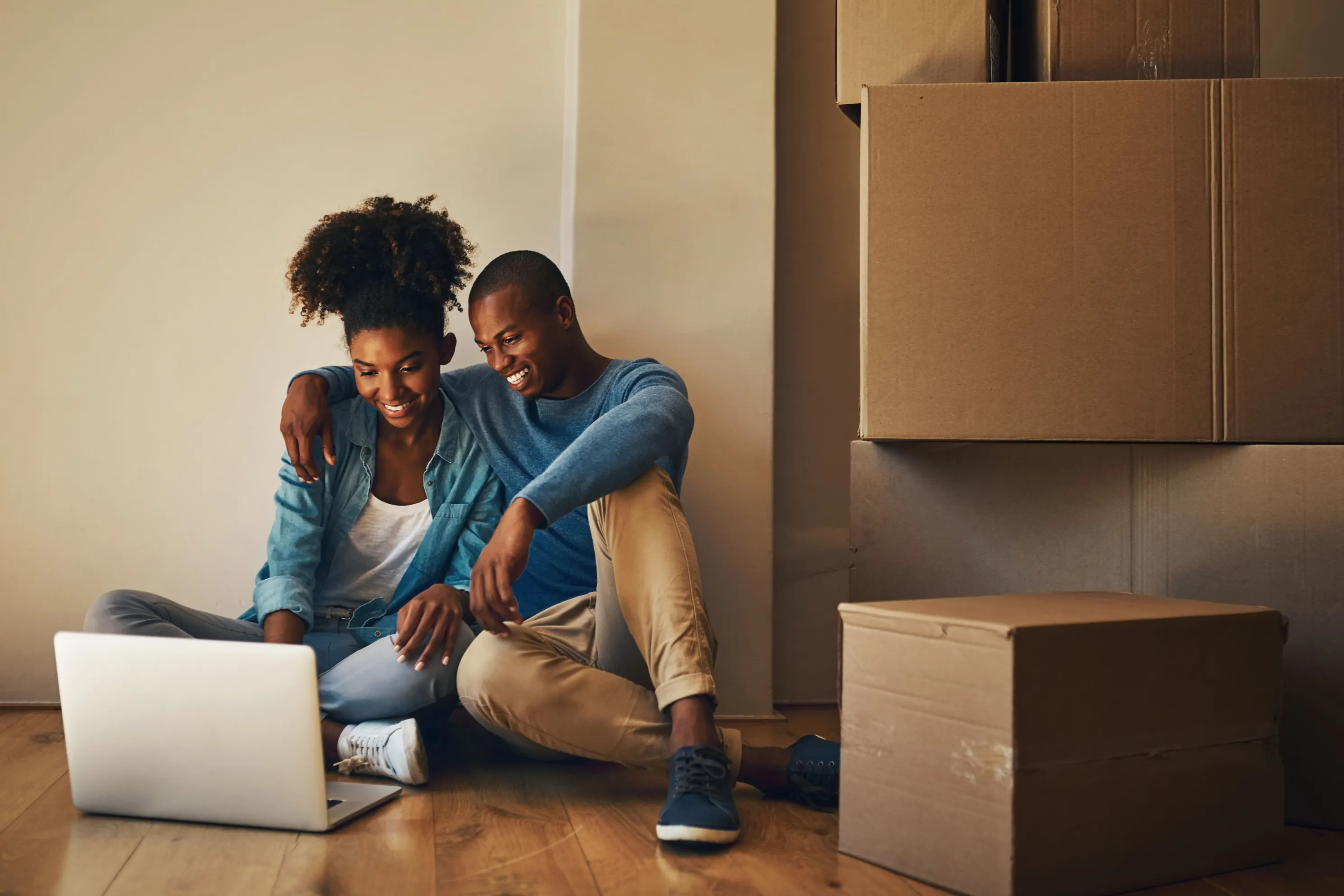 young black couple looking at computer with boxes around them