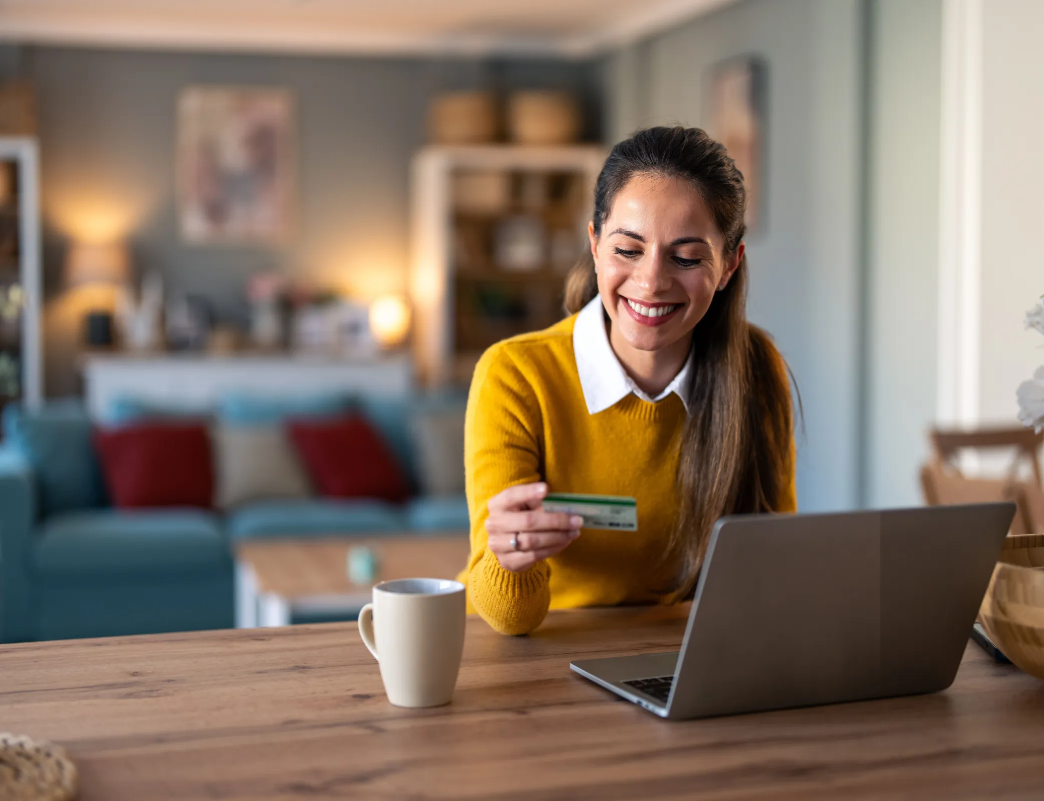 Woman smiling and looking at her credit card on the computer