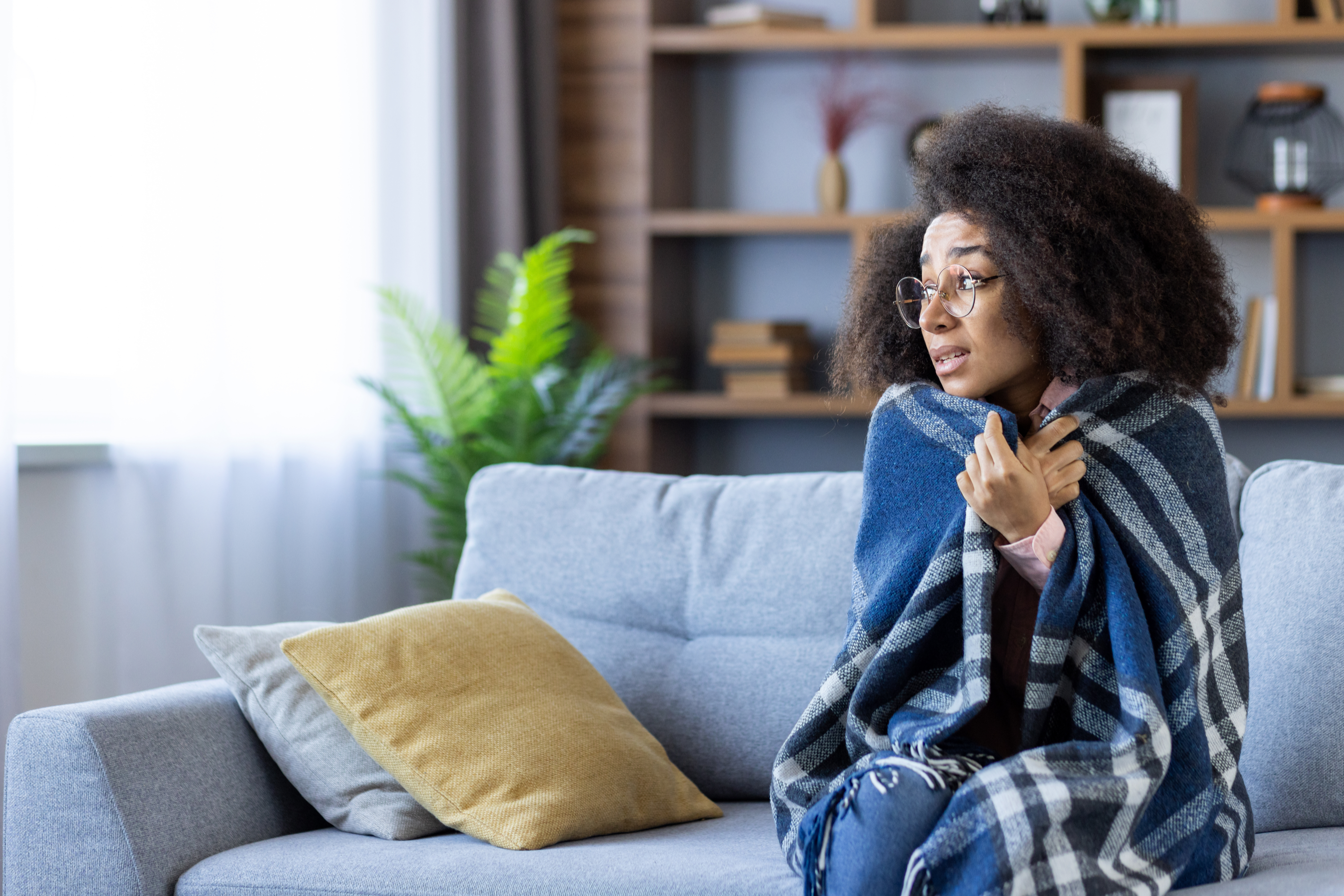 young woman holding blanket over shoulders at home