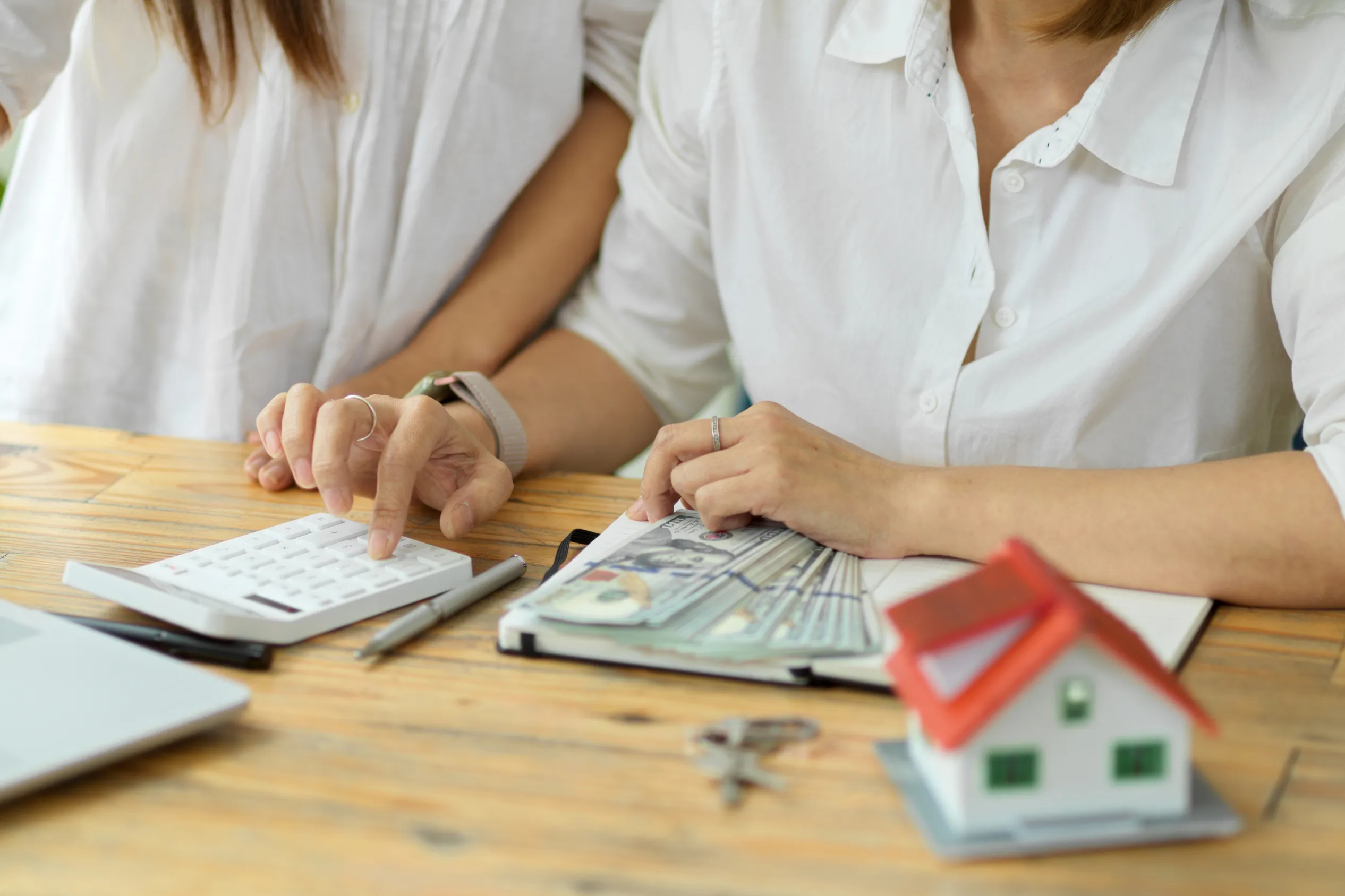 Women sitting at table using a calculator to budget